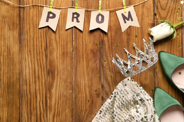 Flags with word PROM, tiara, rose, dress and heels on wooden background