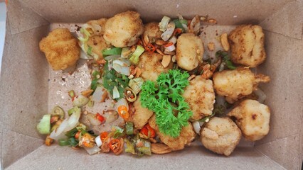 A pack of tofu in the box serve with chili and some spices to male it more delicious and more tasteful