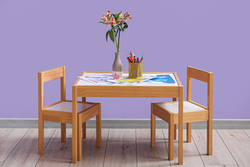 Vase with alstroemeria flowers, pencils and coloring pages on table in children's room