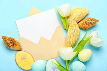Envelope with blank card, flowers, eggs and treats on blue background. Novruz Bayram celebration