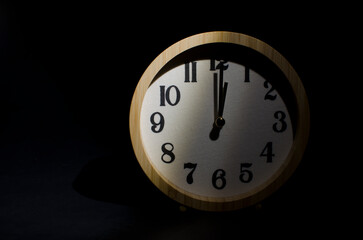 Wooden clock showing 12 o'clock in the darkness.