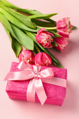 Gift box and beautiful tulip flowers on pink background. Hello spring