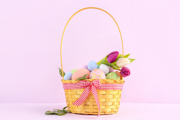 Fototapeta na wymiar Basket with Easter eggs and tulip flowers on pink background