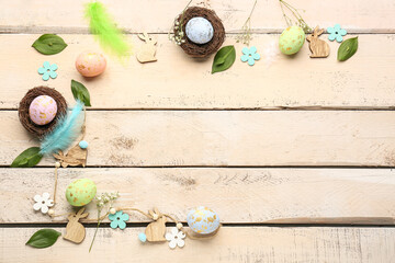 Composition with Easter eggs, feathers, plant leaves and gypsophila flowers on light wooden background