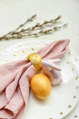 Stylish table setting with Easter egg, ceramic bunny and willow branches on light background, closeup