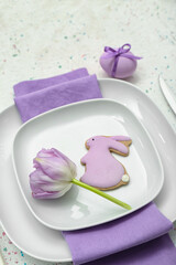 Table setting with Easter egg, bunny and tulip flower on white background