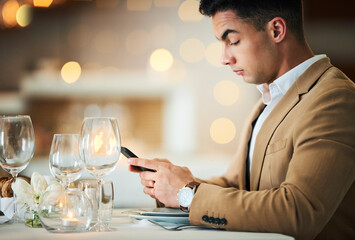 Man, texting and phone at restaurant table for food, night and waiting for valentines day date. Young male, smartphone and wine glass for fine dining, bottle service or drink at dinner celebration