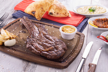 Grilled beef steaks with spices. on wood background with sauce 