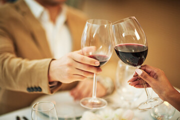Toast, wine and hands of couple in restaurant for romantic dinner, date and anniversary celebration. Relationship, fine dining and man and woman cheers together for social drinks, alcohol and relax