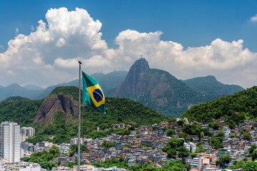 Brazilian flag in foreground and  Christ looking at Favela (Shanty Town) in Rio De Janeiro, Brazil