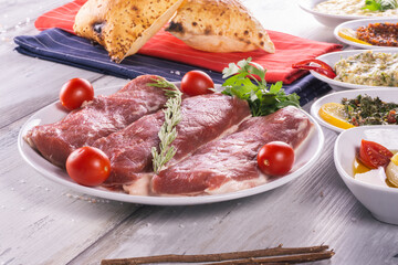 Raw beef steak with spices and tomato wood background, on plate