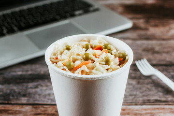 Instant noodles soup ready to eat in the white plastic cup as lunch at office and working with computer laptop in Mexico Latin America
