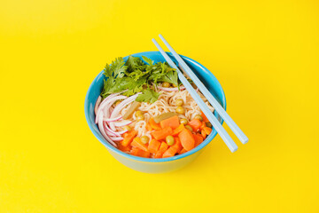 Instant noodles ramen soup on bowl and chopsticks on yellow background