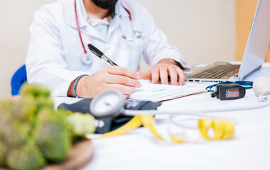 Close-up of nutritionist writing on notepad. Hands of male nutritionist taking notes at his desk,...