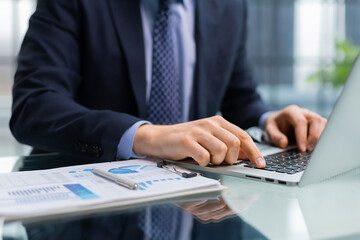 Businessman hands typing at laptop keyboard working at desk.