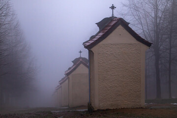 Stations of the Cross on a hill in winter fog. Clouds before sunset hiding buildings of the Stations of the Cross.