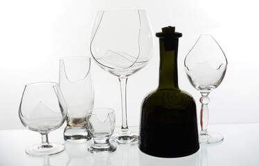 Transparent broken glasses and a dark bottle of wine.
