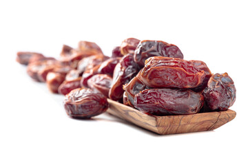 Dates in a wooden dish isolated on a white background.