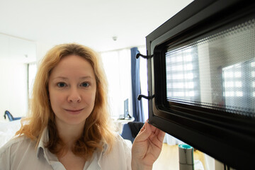 microwave oven, a woman in the kitchen opened the microwave to get cooked food
