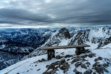 Bank auf dem Wetterstein mit Blick ins winterliche Tirol