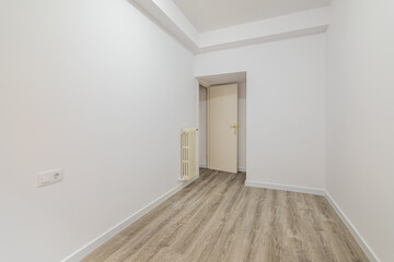 Empty room with laminate flooring and newly painted white wall in refurbished apartment with corridor leading to other rooms. Repair and construction concept.