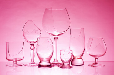 Transparent broken glasses on a pink background.