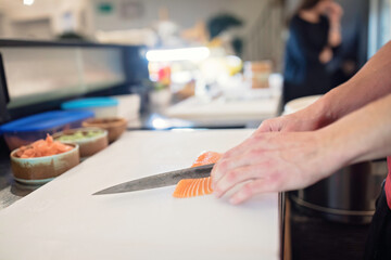 Expert sushi chef carefully cuts fresh salmon for delicious rolls. Perfect for food seafood photography. Watch as a skilled chef prepares juicy salmon sushi rolls. Ideal for gourmet and foodie content