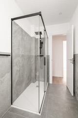 Bathroom with gray granite walls. The shower cabin is enclosed by glass transparent sliding doors...