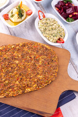 Turkish pizza lahmajun with minced lamb and beef on a thin crust with vegetables and herbs, Wooden table, top view, flat lay, copy space