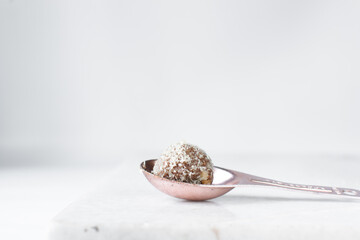 Coconut and chocolate truffles in copper spoon, homemade chocolate bonbons on white background, desiccated coconut coated truffles