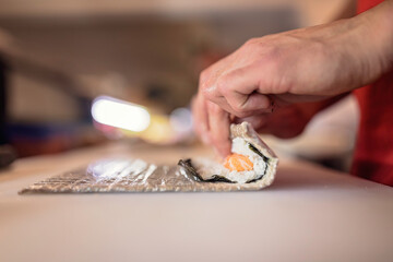 A sushi chef skillfully prepares salmon and avocado rolls. Perfect for culinary, cooking, and foodie content. Tasty salmon rolls with a side of soy sauce and wasabi