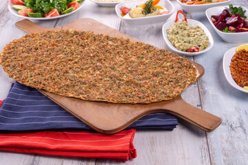 Turkish pizza lahmajun with minced lamb and beef on a thin crust with vegetables and herbs, Wooden table, top view, flat lay, copy space