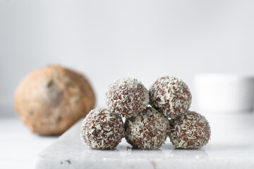 Coconut and chocolate truffles on marble tray, homemade chocolate bonbons on white background, desiccated coconut coated truffles
