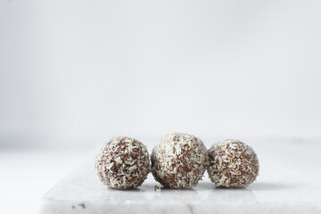 Coconut and chocolate truffles on marble tray, homemade chocolate bonbons on white background, desiccated coconut coated truffles