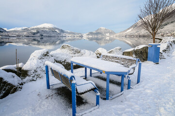 Snow-covered benches by the sea