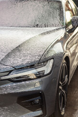 Vertical photography close up concept of washing car with foam.