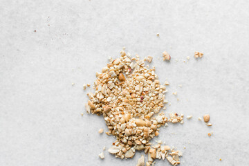 Top view of chopped roasted peanuts on a marble table