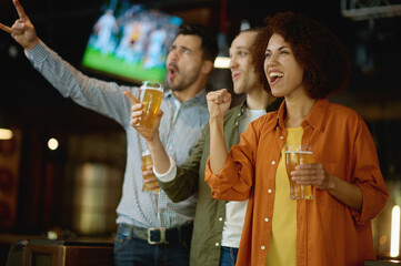 Happy football fans drinking beer and celebrating victory at sport bar