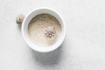 Top view of coconut and chocolate truffles, homemade chocolate bonbons in a ramekin, desiccated coconut coated truffles