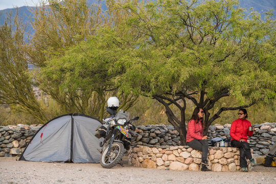 Two women sitting beside motorbike camp at the Ruinas de Quilmes