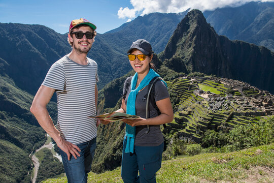 Couple at Inca ruins looking at camera smiling, Machu Picchu, Peru