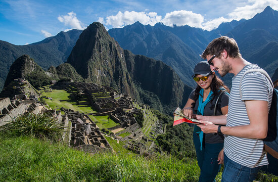 Couple at Inca ruins looking at folding map, Machu Picchu, Peru