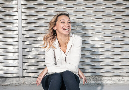 Portrait of A Young Woman with Big Smile in Front of Metallic Wall