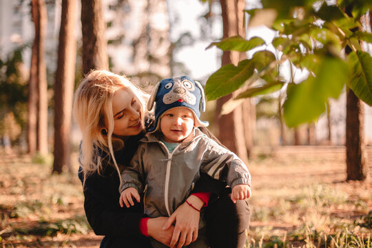 Happy Young Mother Embracing Her Little Toddler Son In Park In Autumn