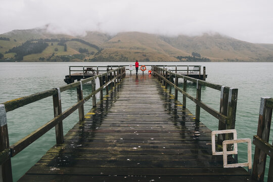 Woman on a red jacket standing at Port Levy Jetty, Banks Peninsula, NZ