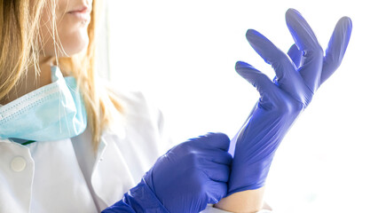 Medicine and Surgery theme: female nurse putting on protective blue gloves