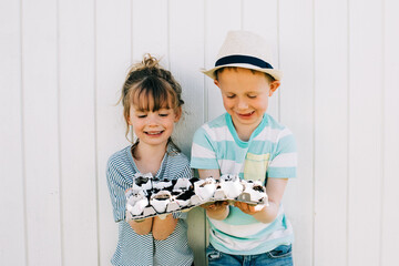 siblings holding their planted egg shells smiling proudly