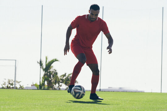 Fototapeta Full length of African American soccer player playing on grass pitch