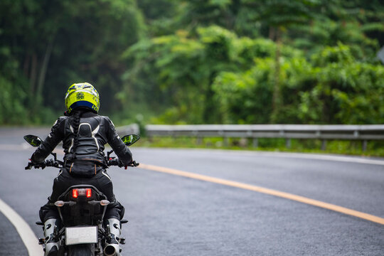 woamn riding her motorcycle on empty highway in Thailand