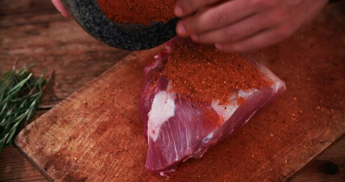 Cropped image of a dry meat rub made of spicy seasoning being rubbed into a piece of quality raw pork